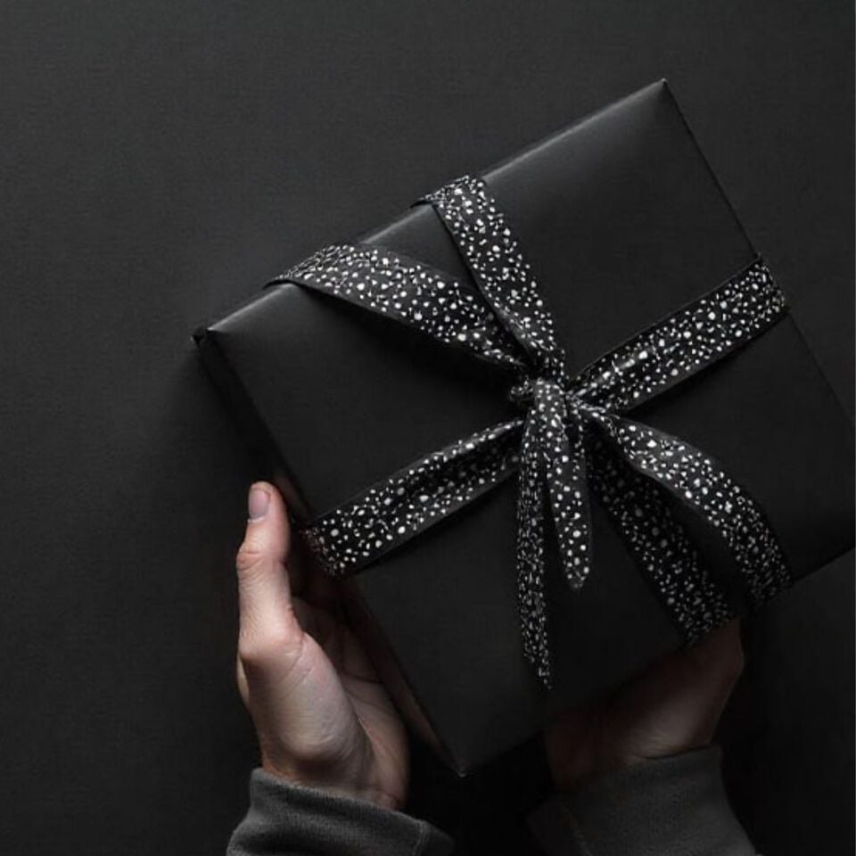 Rosenthal Vases of Phases black vase, Versace Lumiere whiskey tumbler and Rosenthal Block Glass clock before blured out living room background.