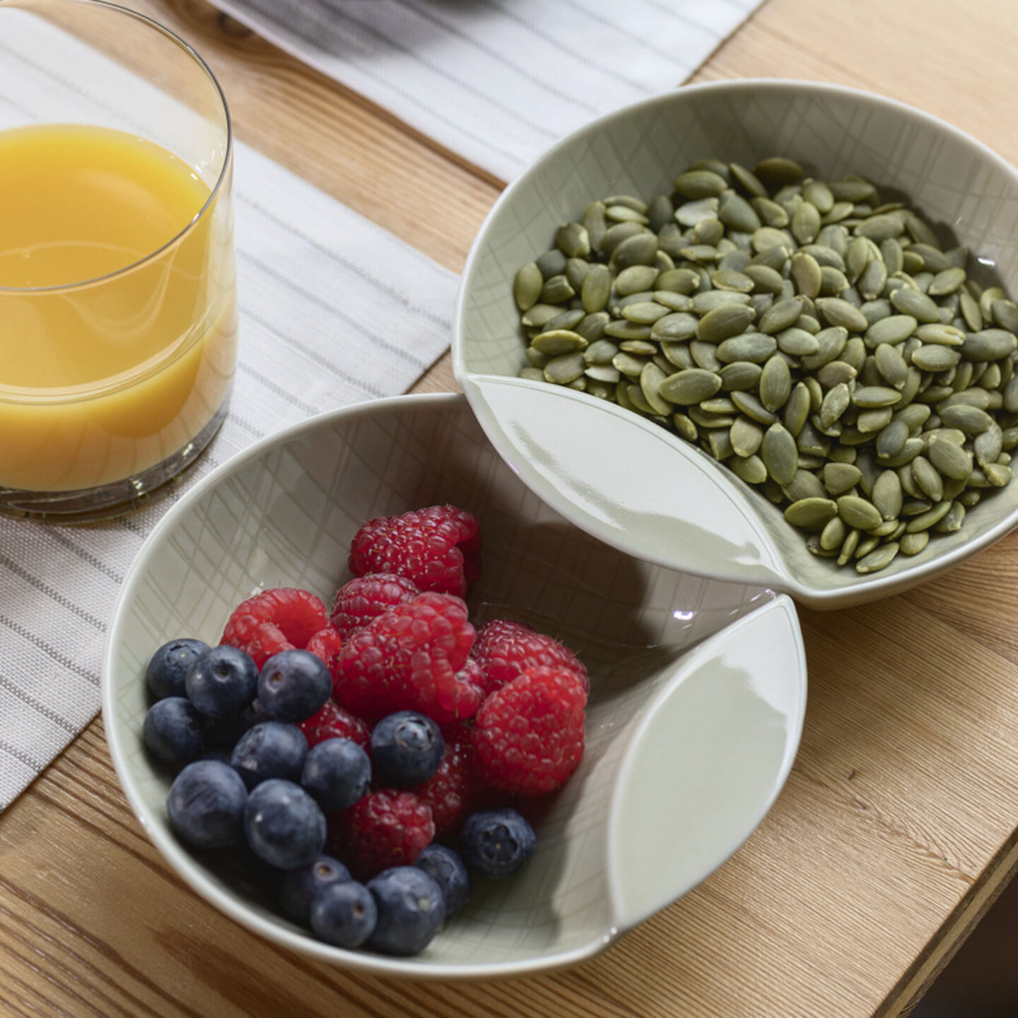 Two Mesh Walnut bowls filled with rasberries & pumpkin seeds