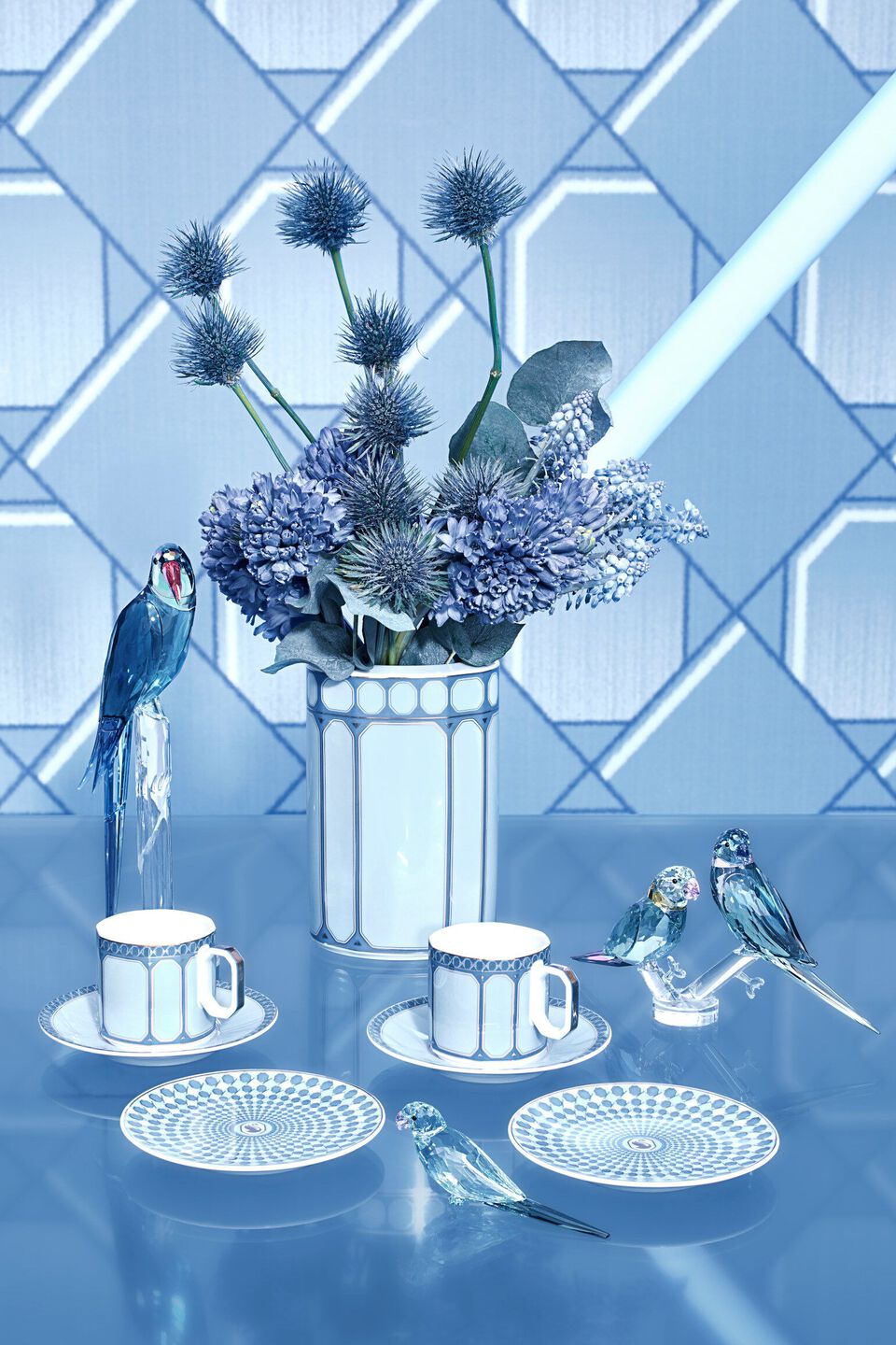 Blue porcelain plates, tea cup, tea pot on blue table on blue background with a model in blue