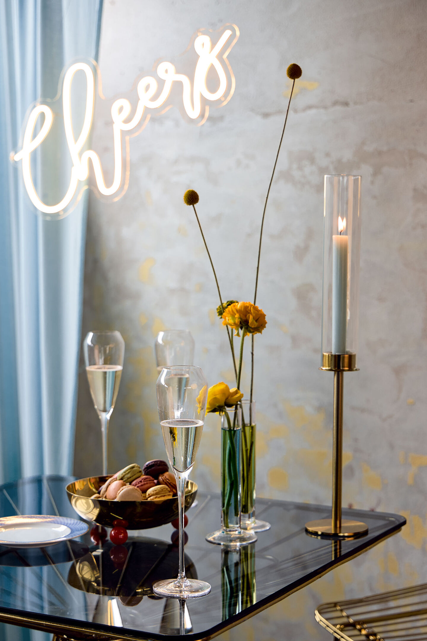 TAC champagne glasses on glass table with a slogan "cheers" above