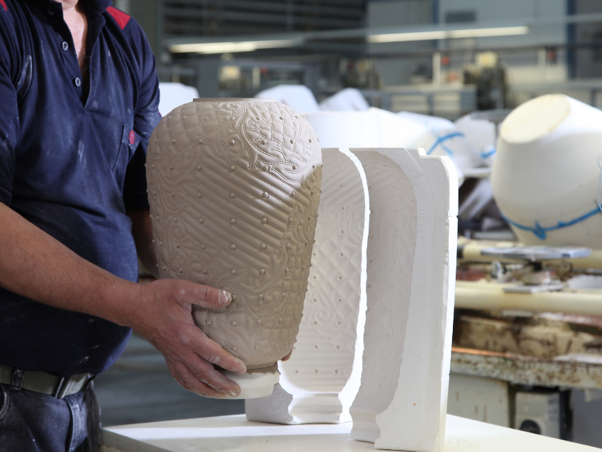 Porcelain manufacturing: An employee removes an unfired, textured vessel from a two-part mould in a workshop.