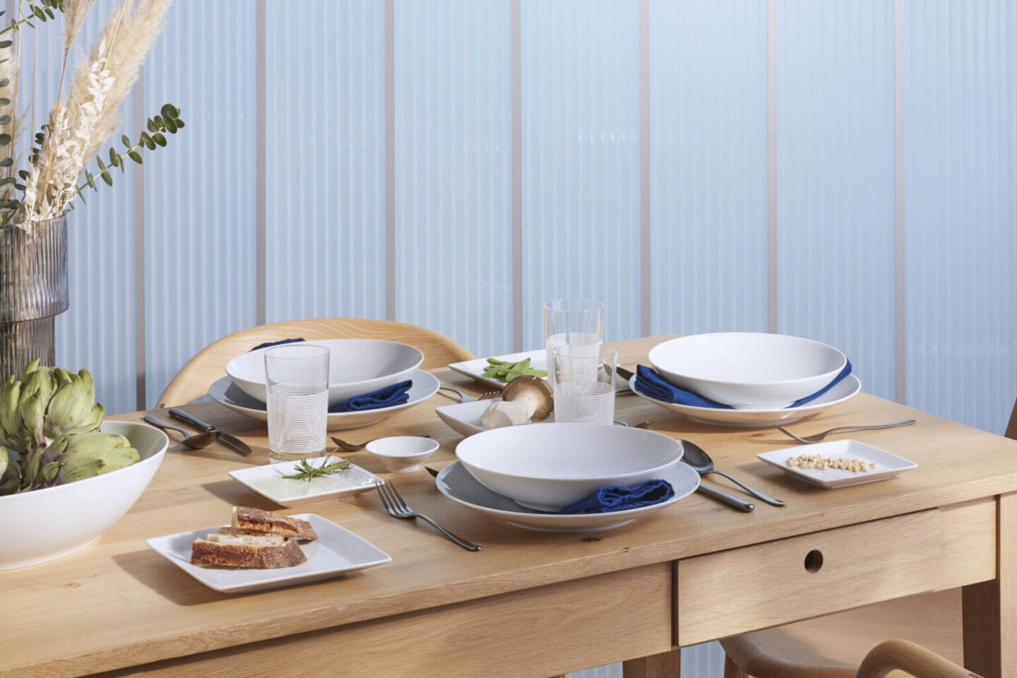 A table set with Thomas Loft White plates, and platters with blue napkins