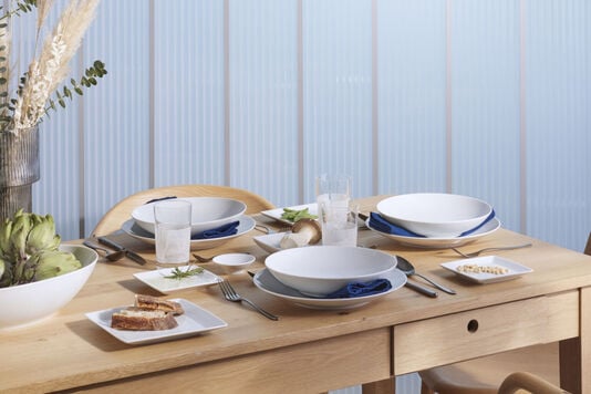 A table set with Thomas Loft White plates, and platters with blue napkins