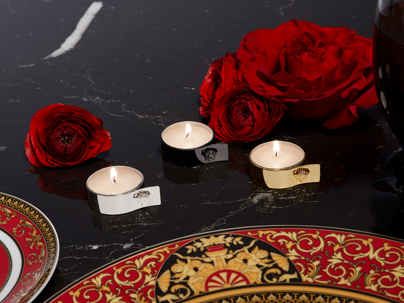 Versace Medusa Tea Lights & Napkin Rings on a black marble table with red roses in the background